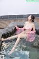 A woman in a pink kimono sitting in a pool of water.