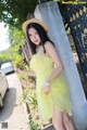 A woman in a yellow dress and straw hat posing for a picture.