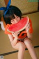 A young girl sitting on the floor eating a slice of watermelon.