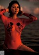 A woman in a red bodysuit sitting in the water.