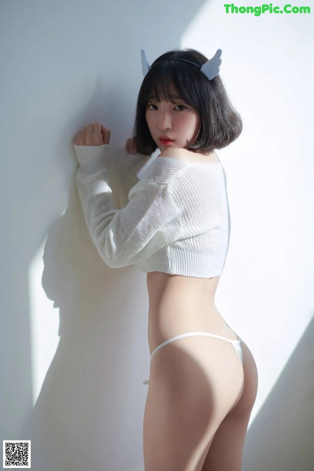 A woman in a white sweater and a white thong.