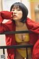 A woman in a yellow bikini and a red cardigan.