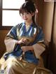 A woman in a blue and gold kimono sitting by a window.