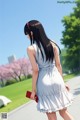 A woman in a white dress walking down a sidewalk.